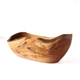 A rustic handcrafted wooden bowl with a live edge, showcasing natural wood grain patterns in warm brown and tan tones, set against a plain white background.
