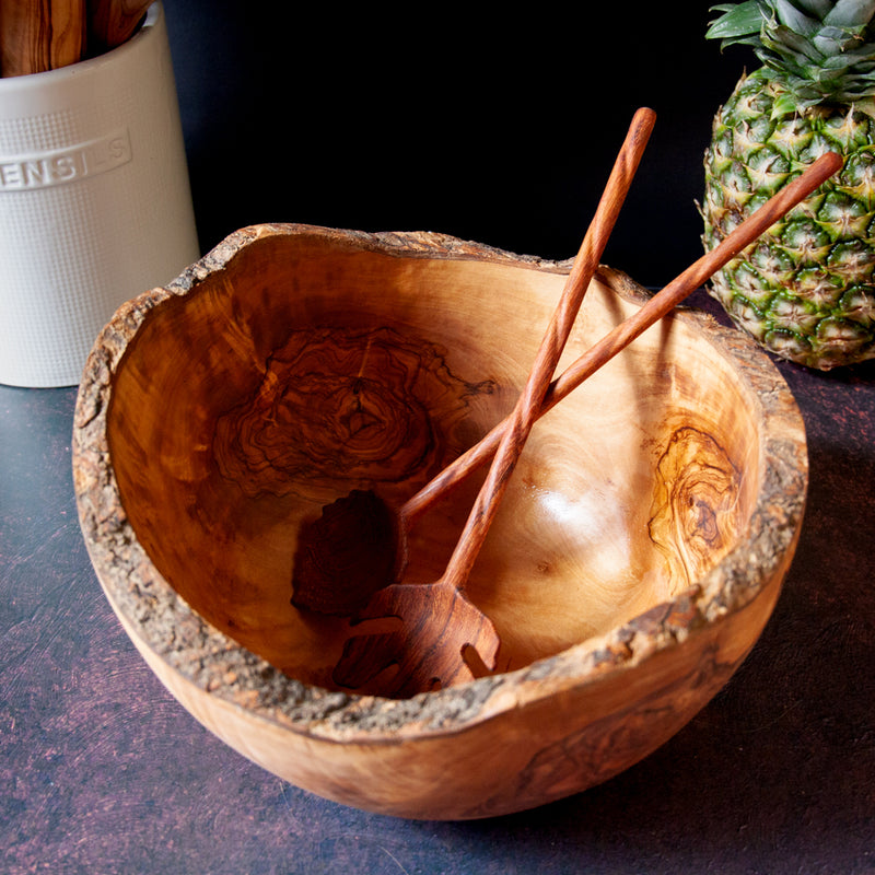 Big rustic wooden salad bowl with pair of leaf shaped salad servers