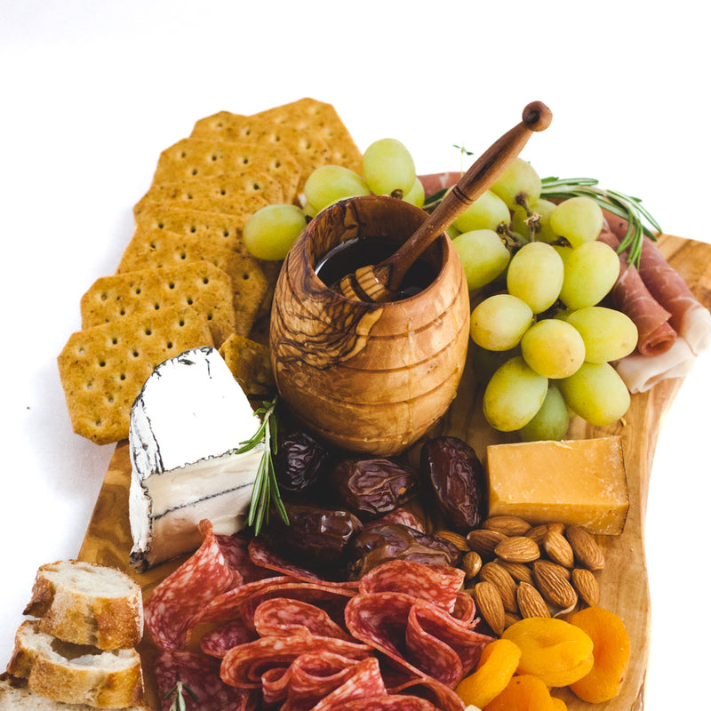 Charcuterie board with meat, cheese, crackers and a wooden honey pot with honey dipper