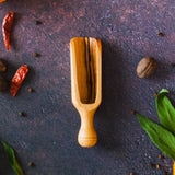 Large wooden scoop on rusty background with red peppers, green leaves and oranges