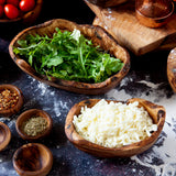 two sizes of rustic wooden dishes, filled with pizza ingredients on a dark flour dusted background