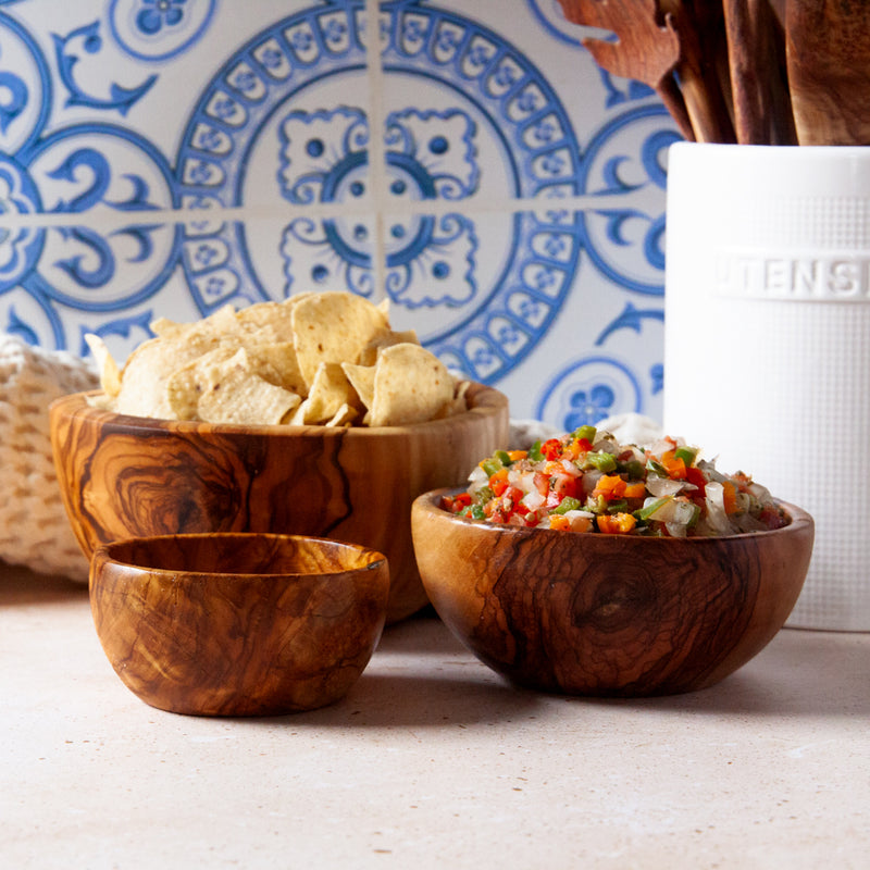 Three wooden bowls with chips and salsa on a blue background