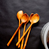 five wooden pointed spoons on a black background