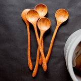 pile of five hand carved curvy wooden spoons on a black background