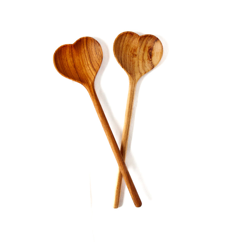 Two heart shaped wooden spoons on a white background