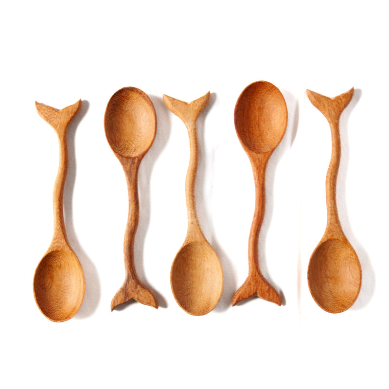 Five wooden spoons with whale tails on a white background