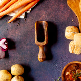 XL wooden scoop on dark background surrounded by ingredients for beef stew
