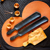 Black appetizer Paddle boards with wood pinch bowls on a table
