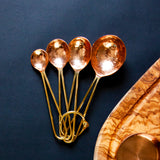 Copper Measuring Spoons fanned out on a black background