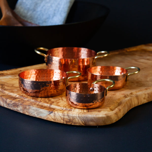 Copper measuring cups on olive wood serving board