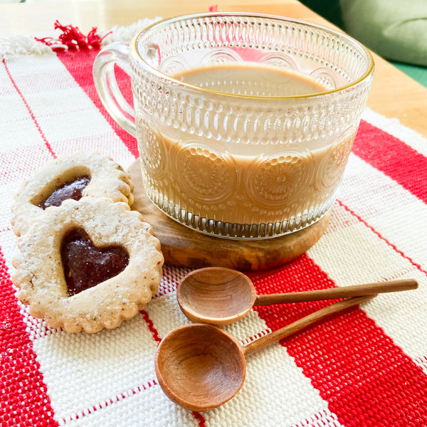 Two coffee spoons with cookies, coffee and placemat